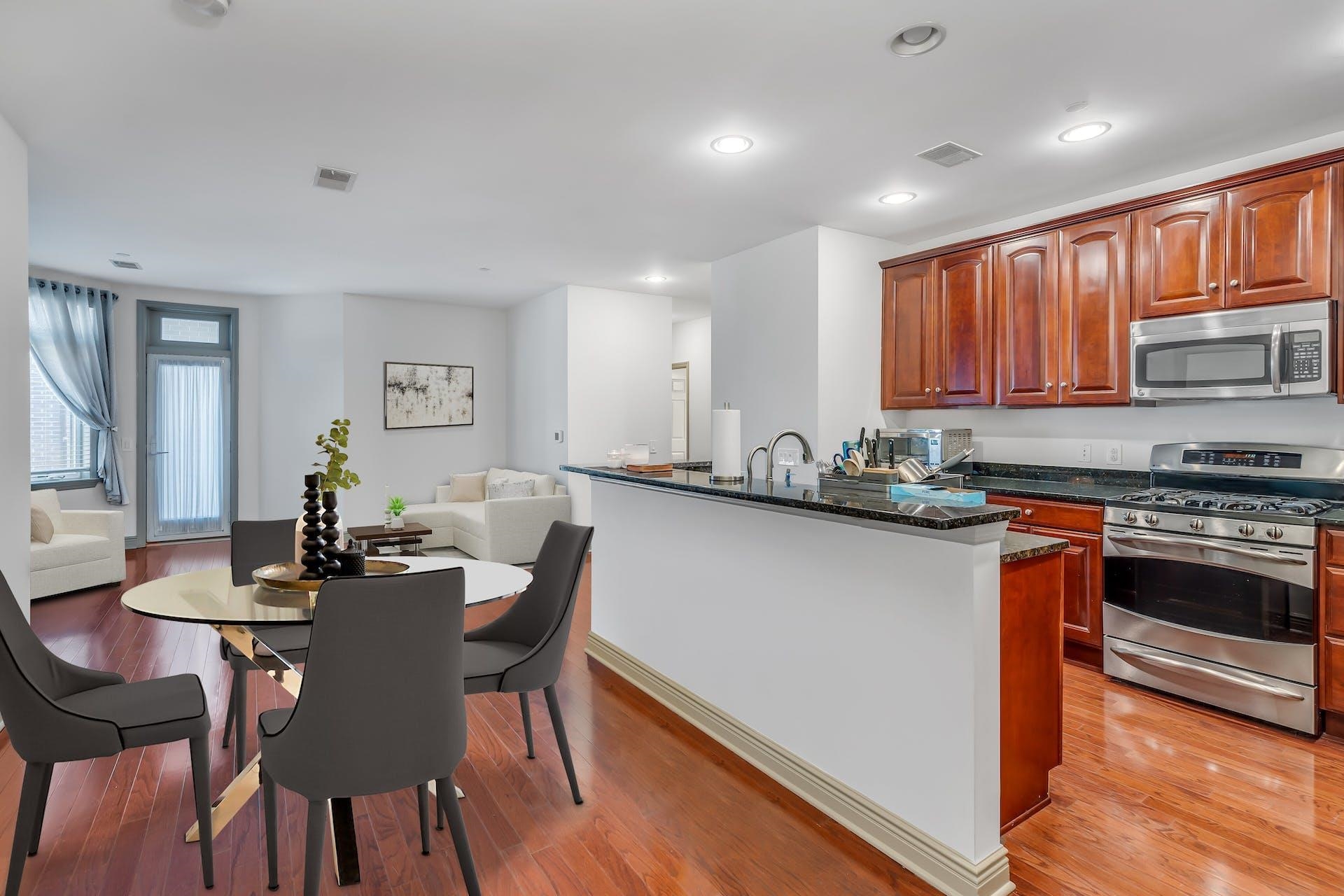 7400 River Road, Unit 315 North Bergen, NJ 07047 - Photo 4 of 19 a kitchen with stainless steel appliances granite countertop a stove a sink a microwave a dining table and chairs with wooden floor