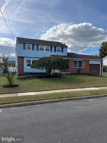 a view of a house next to a big yard and large trees