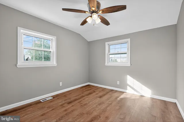 a view of an empty room with window and wooden floor