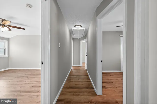 a view of a hallway with wooden floor and a living room
