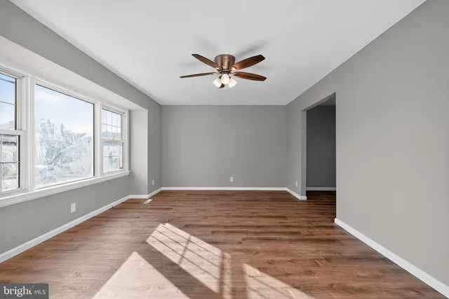 a view of an empty room with window and a ceiling fan