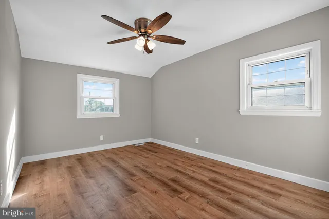 a view of a big room with wooden floor and windows