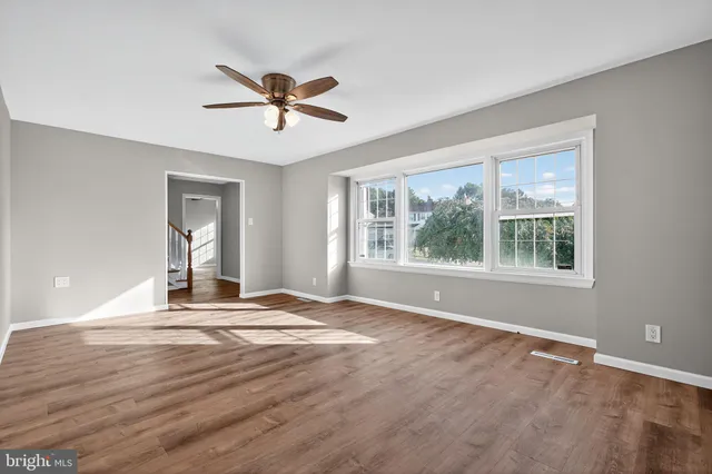 a view of an empty room with window and wooden floor