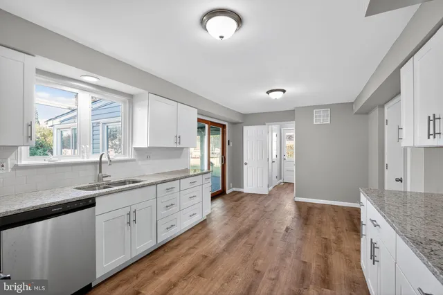 a view of a kitchen with sink and dishwasher with wooden floor