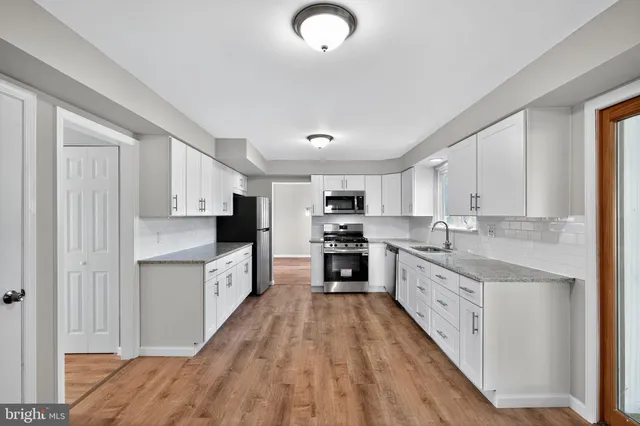 a large kitchen with stainless steel appliances granite countertop a stove a sink dishwasher and a refrigerator