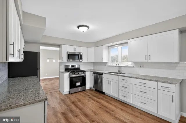 a kitchen with granite countertop a sink stainless steel appliances and cabinets