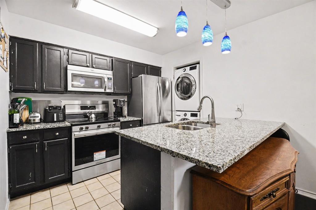 5616 Preston Oaks Road, Unit 102 Dallas, TX 75254 - Photo 6 of 11 a kitchen with kitchen island granite countertop a stove a sink dishwasher and microwave with wooden cabinets