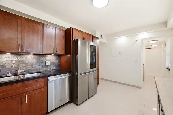 a kitchen with stainless steel appliances granite countertop a refrigerator and a sink
