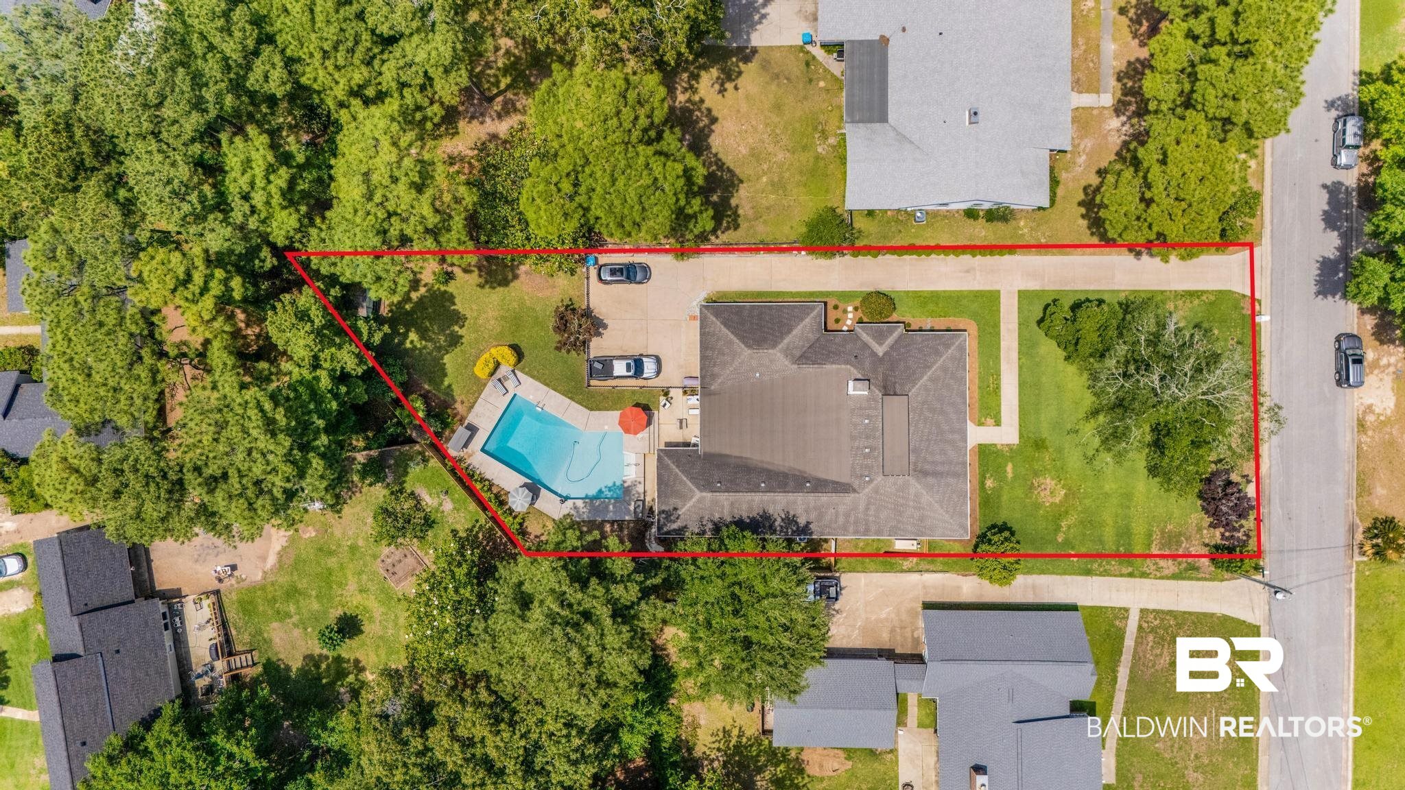 83 Caisson Trace Daphne, AL 36527 - Photo 62 of 63 Expansive property featuring a large swimming pool with surrounding patio space, a substantial main residence with a gabled roof, and extensive paved driveway parking