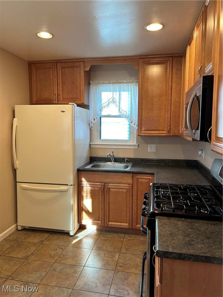 1094 Plainfield Road Cleveland, OH 44121 - Photo 10 of 41 Kitchen with sink, light tile patterned floors, fridge, and range