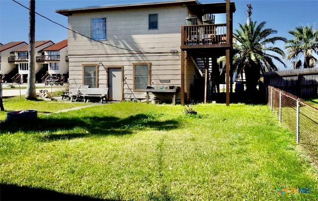 a view of a house with a yard plants and large tree