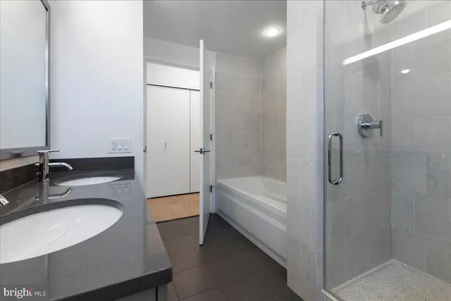 a bathroom with a granite countertop sink a mirror a bathtub and shower