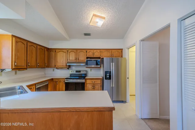 a kitchen with stainless steel appliances granite countertop a refrigerator a sink dishwasher a stove and a microwave oven