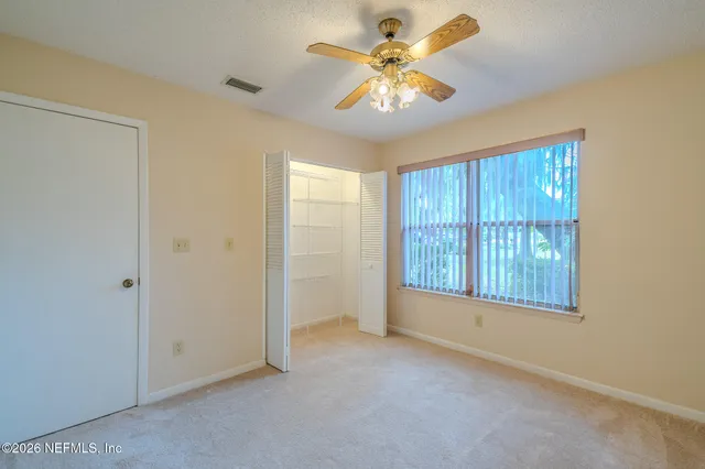 an empty room with chandelier fan and windows