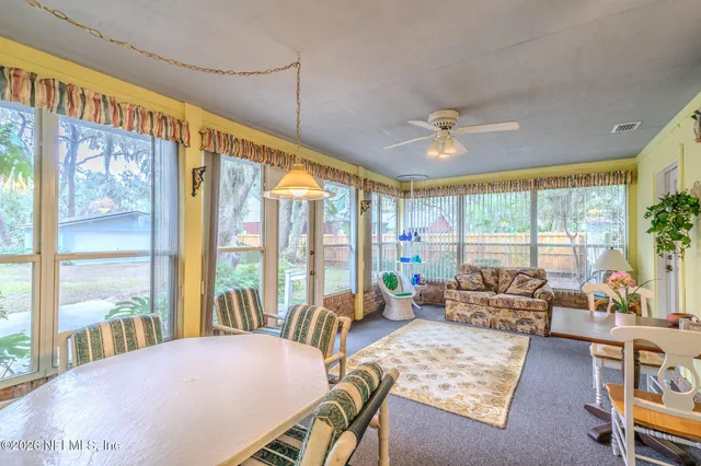 a living room with furniture large windows and wooden floor