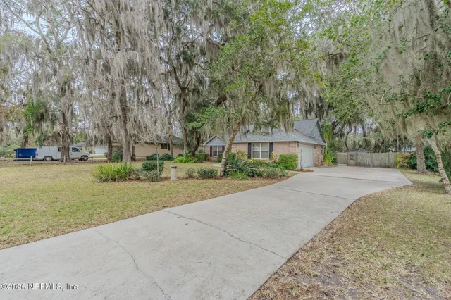 a front view of a house with a yard and large trees