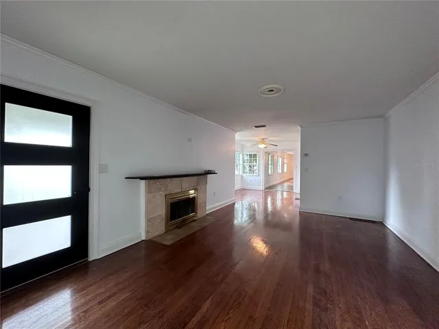 an empty room with wooden floor fireplace and windows