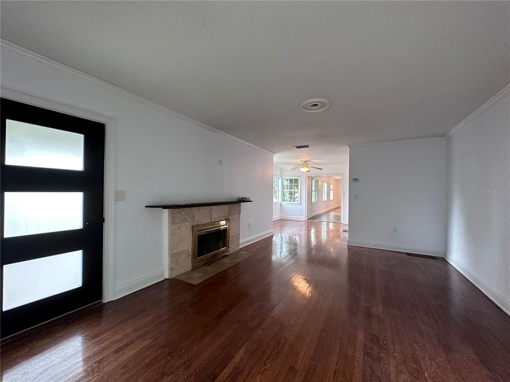 315 Sunburst Court Clearwater, FL 33755 - Photo 2 of 23 an empty room with wooden floor fireplace and windows