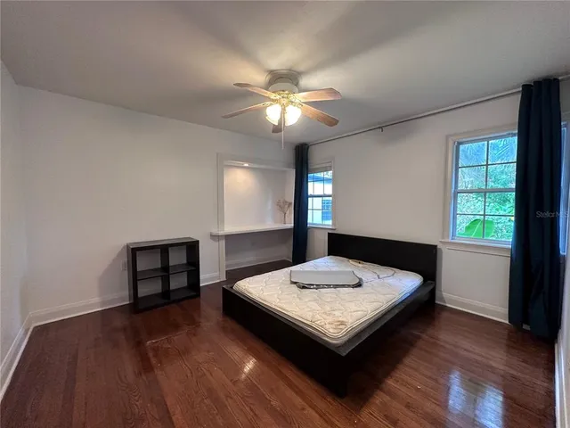 a living room with hard wood floors a bed and a chandelier