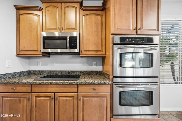 a kitchen with granite countertop white cabinets stainless steel appliances and a counter space
