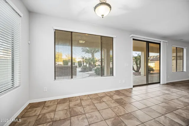 a view of an empty room with window and chandelier fan