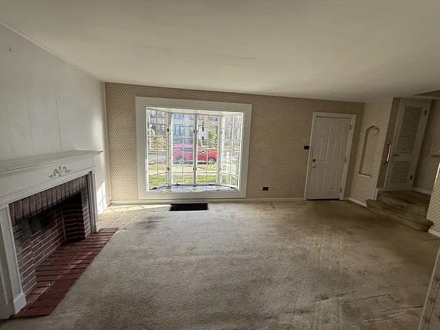 a view of an empty room with a fireplace and a window