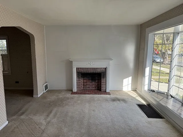a view of an empty room with a fireplace and a window