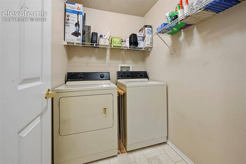 3715 Riviera Grove, Unit 101 Colorado Springs, CO 80922 - Photo 32 of 36 Dedicated laundry area featuring a white paneled door with brass hardware, light-toned walls, and twin wire shelving units for storage