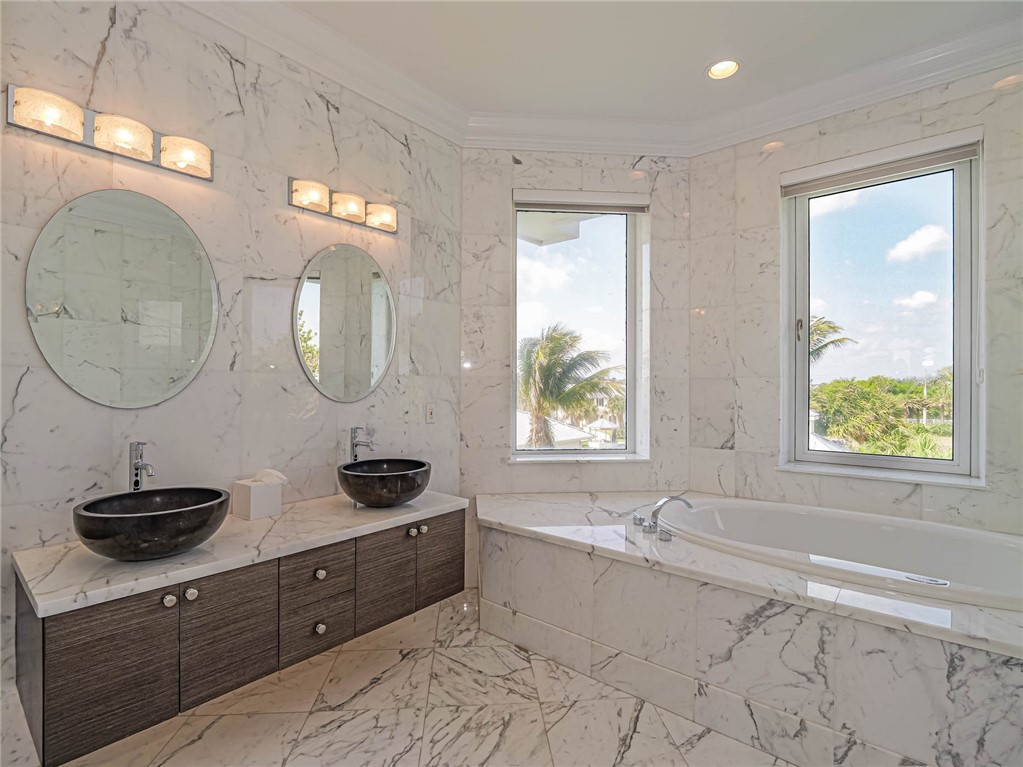 2250 Sanderling Lane Vero Beach, FL 32963 - Photo 18 of 36 a bathroom with a double vanity sink a mirror and a bathtub next to a window