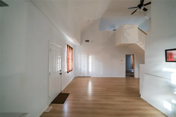 a view of empty room with wooden floor and fan