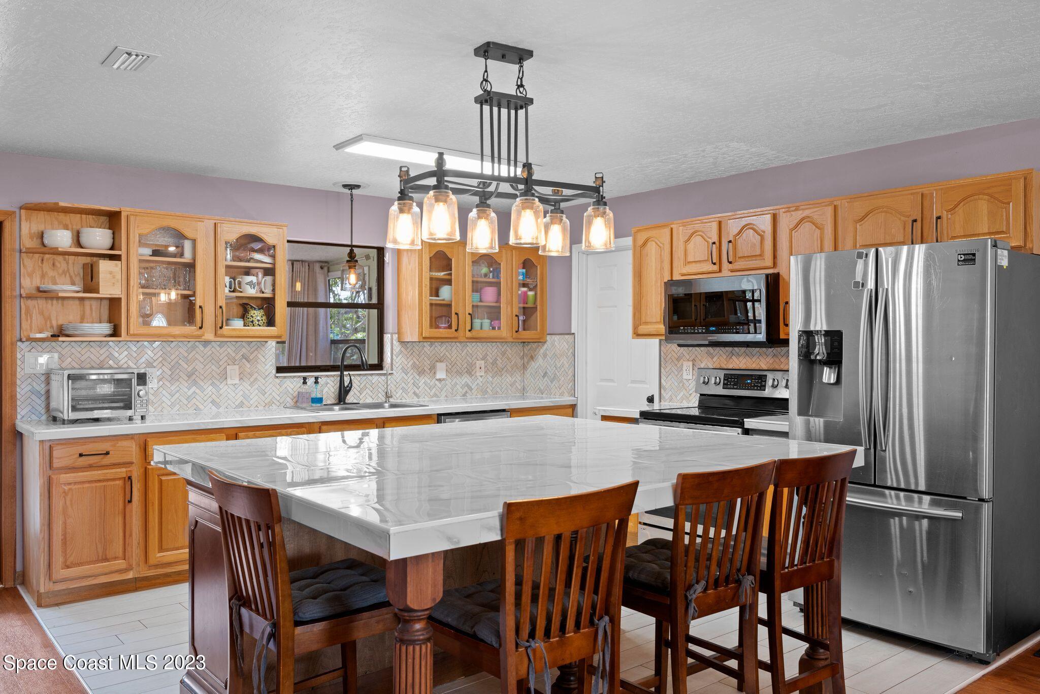 3704 Windsor Drive Cocoa, FL 32926 - Photo 9 of 48 a kitchen with granite countertop a table chairs microwave and refrigerator