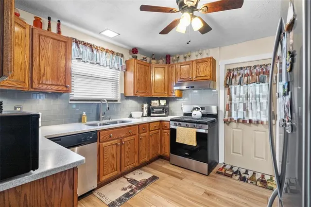 a kitchen with stainless steel appliances granite countertop a sink cabinets wooden floor and a window
