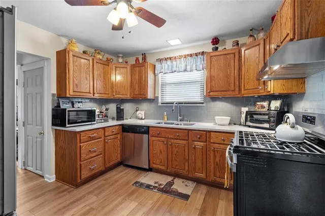 a kitchen with stainless steel appliances granite countertop wooden cabinets a sink a stove a dining table and chairs