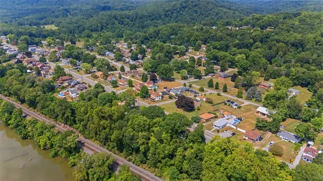 an aerial view of residential house with outdoor space and trees all around