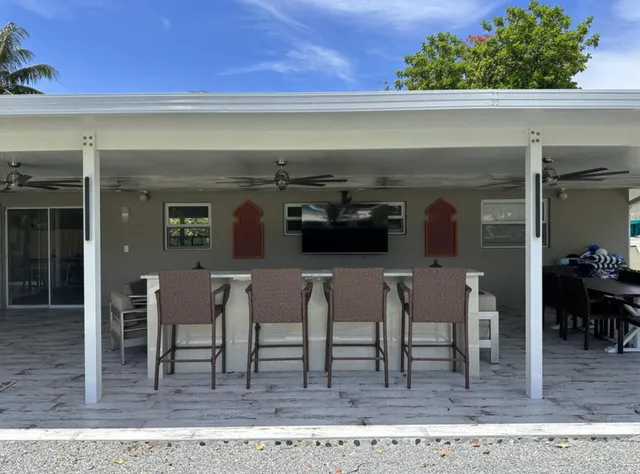 a kitchen with stainless steel appliances kitchen island granite countertop a refrigerator a stove a sink a dining table and chairs with wooden floor