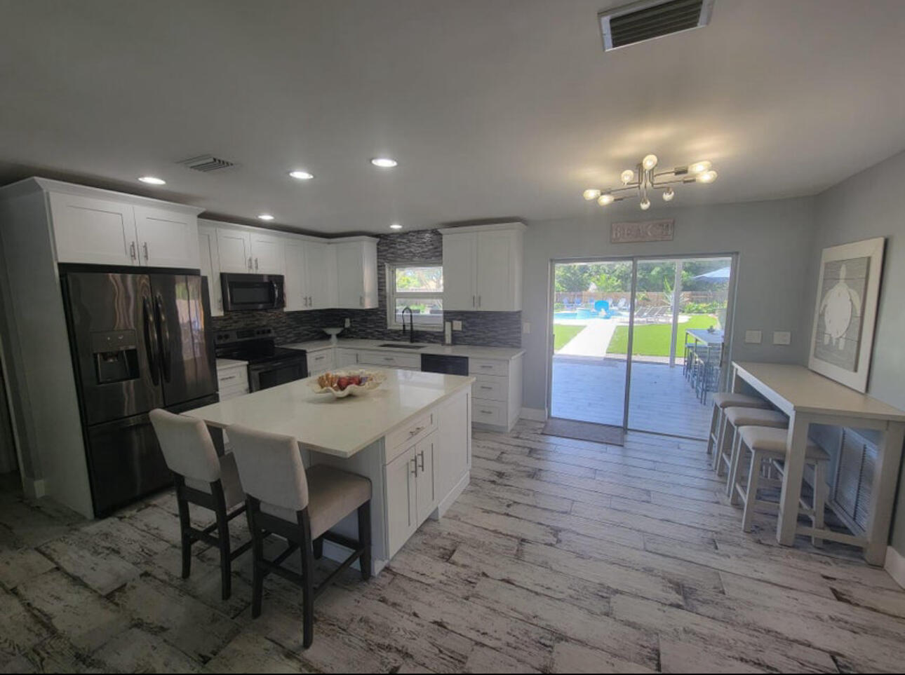 270 Northwest 36th Street Boca Raton, FL 33431 - Photo 59 of 82 a kitchen with stainless steel appliances kitchen island granite countertop a refrigerator a stove a sink a dining table and chairs with wooden floor
