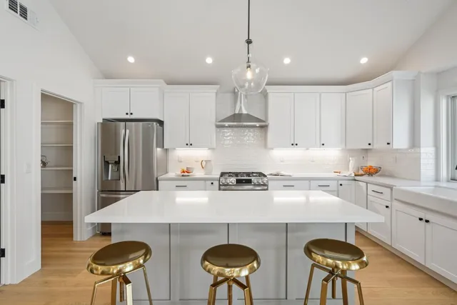 a kitchen with stainless steel appliances a stove a table and chairs in it