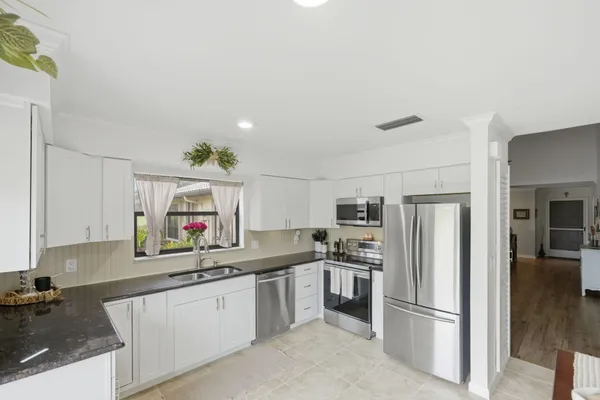 a kitchen with granite countertop a refrigerator sink and stainless steel appliances