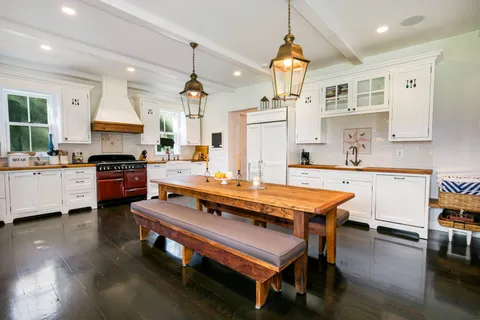 a kitchen with a stove a refrigerator and a dining table with wooden floor