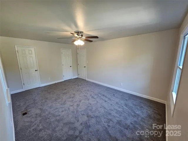 an empty room with a ceiling fan and a window