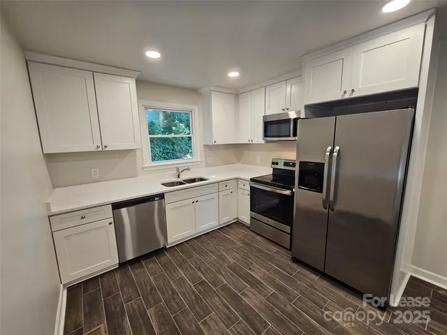 a kitchen with granite countertop white cabinets and stainless steel appliances
