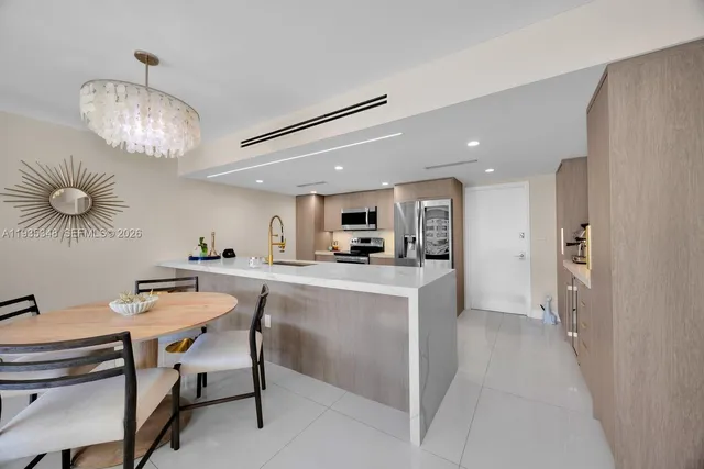 a kitchen with stainless steel appliances kitchen island granite countertop a table chairs and a refrigerator