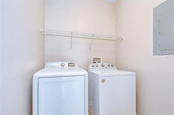 a view of a sign in a garden with potted plants and brick walls