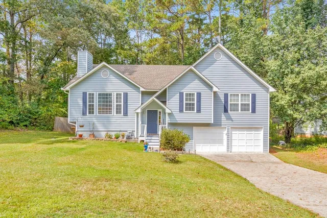 a front view of a house with a garden and trees