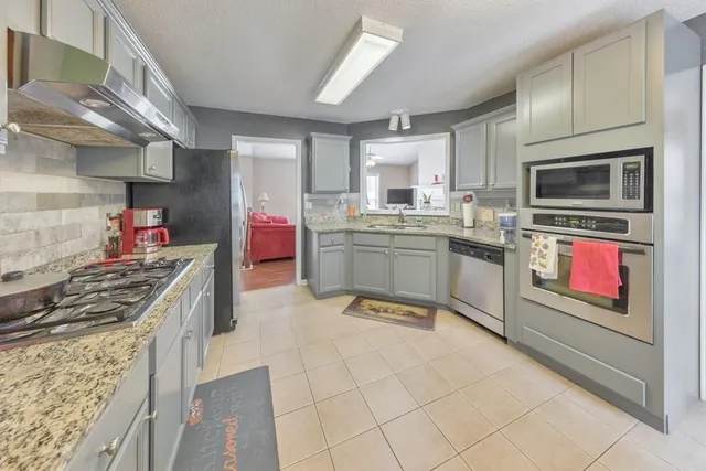 a kitchen with stainless steel appliances granite countertop a stove top oven a sink dishwasher and cabinets