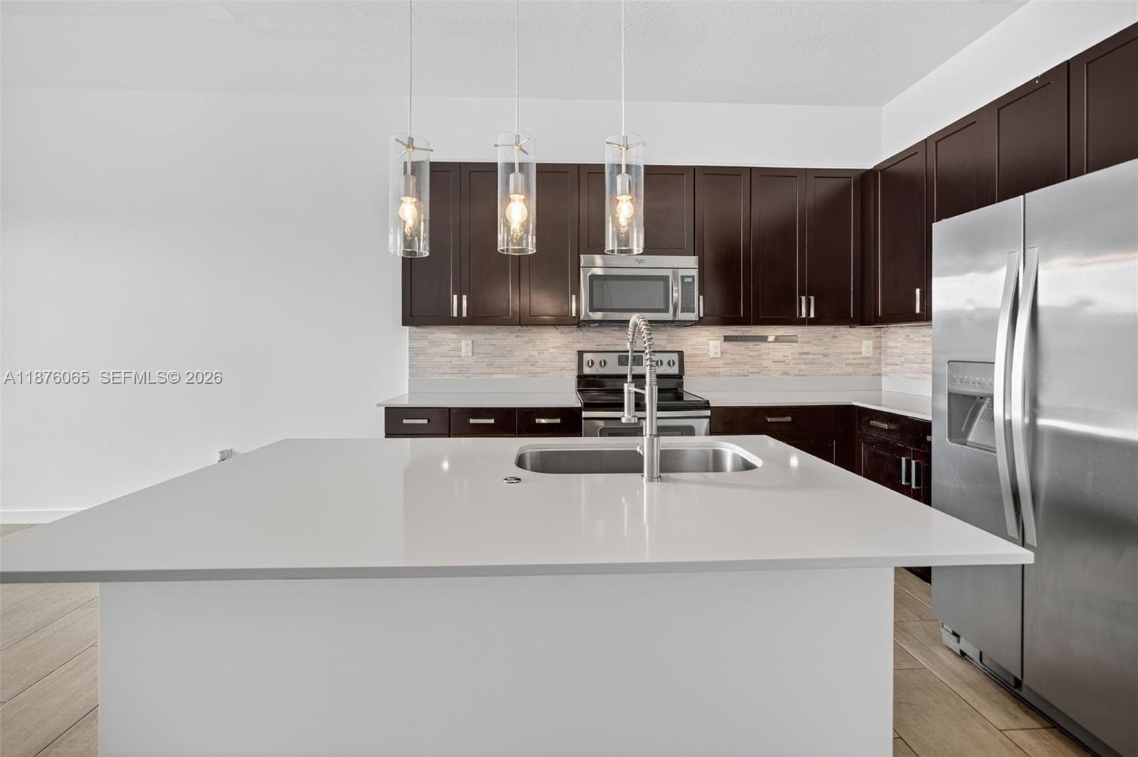 17606 Southwest 149th Place, Unit 17606 Miami, FL 33187 - Photo 11 of 69 a kitchen with kitchen island a sink stainless steel appliances and cabinets