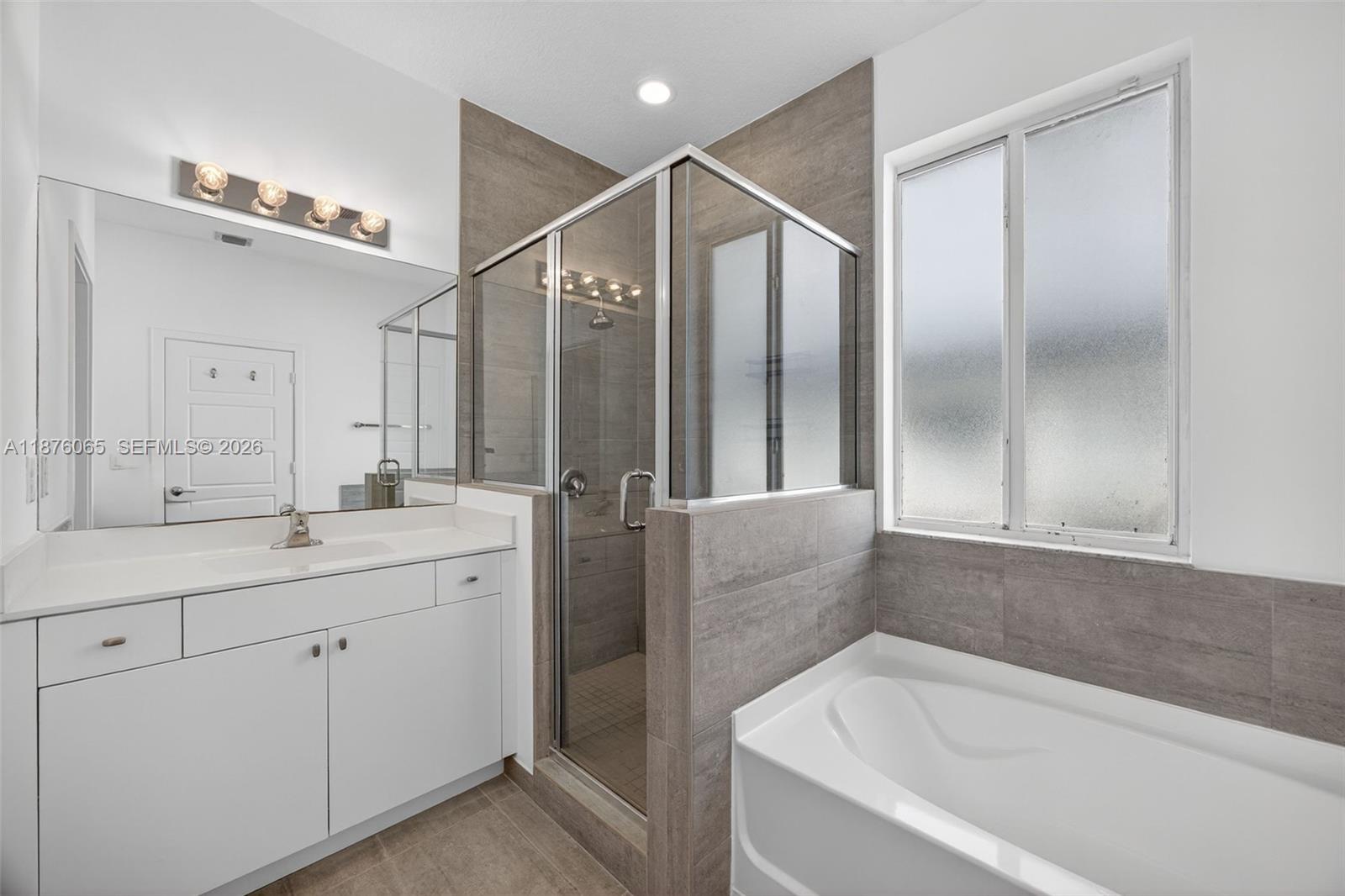 17606 Southwest 149th Place, Unit 17606 Miami, FL 33187 - Photo 31 of 69 a bathroom with a bathtub a double vanity sink and mirror