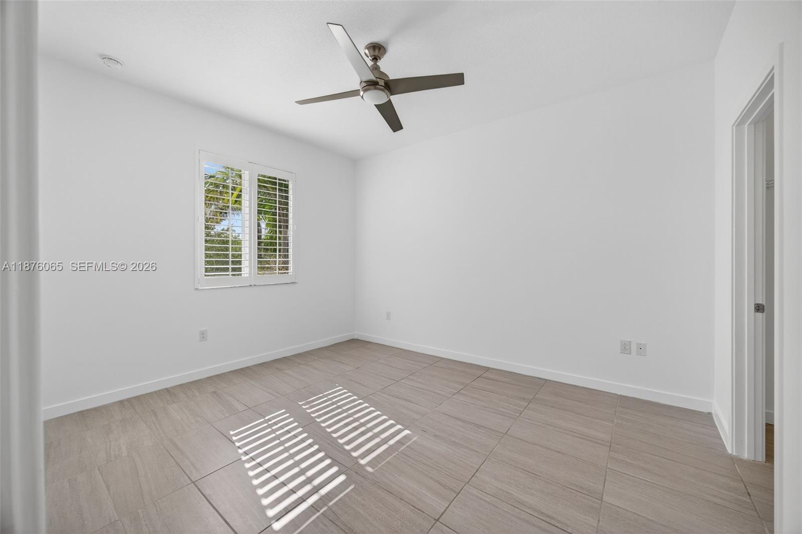 17606 Southwest 149th Place, Unit 17606 Miami, FL 33187 - Photo 47 of 69 an empty room with a window and a ceiling fan