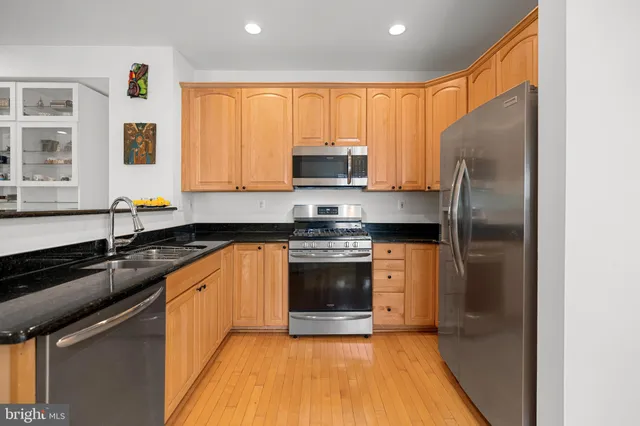 a kitchen with granite countertop stainless steel appliances a sink stove and refrigerator