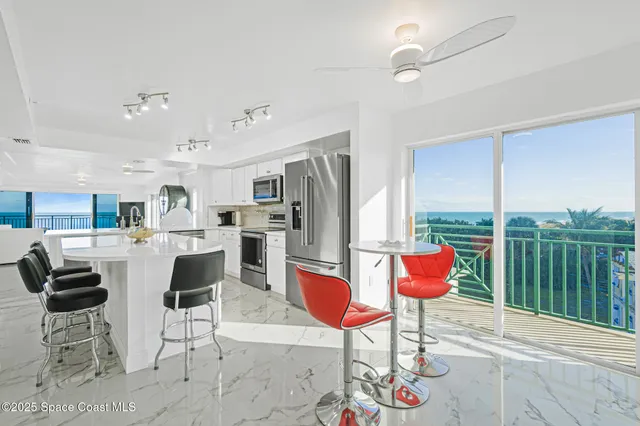 a kitchen with stainless steel appliances kitchen island granite countertop a refrigerator a stove top oven and a dining table with wooden floor